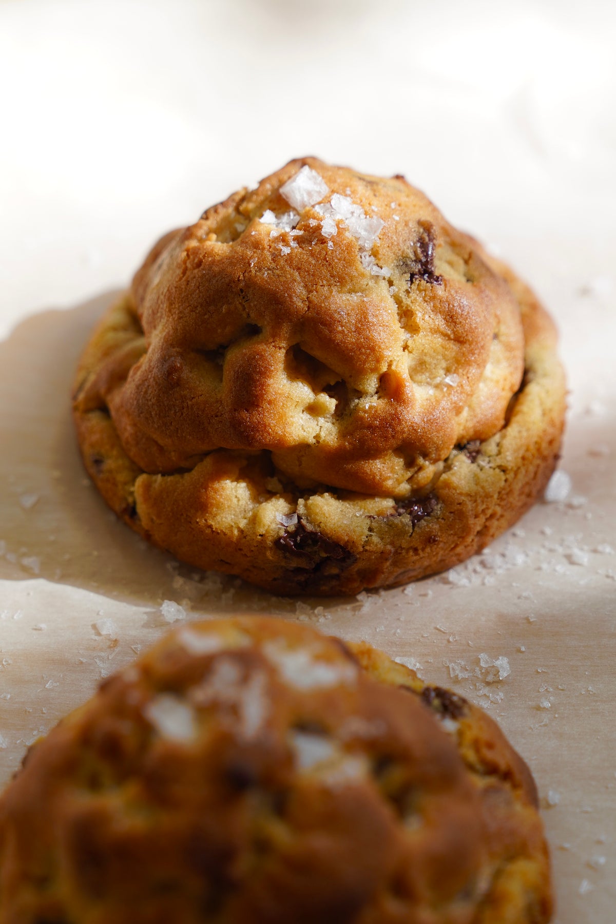 Tall NYC style chocolate chip cookie with flaky salt on parchment, made with the Baked Up master dough